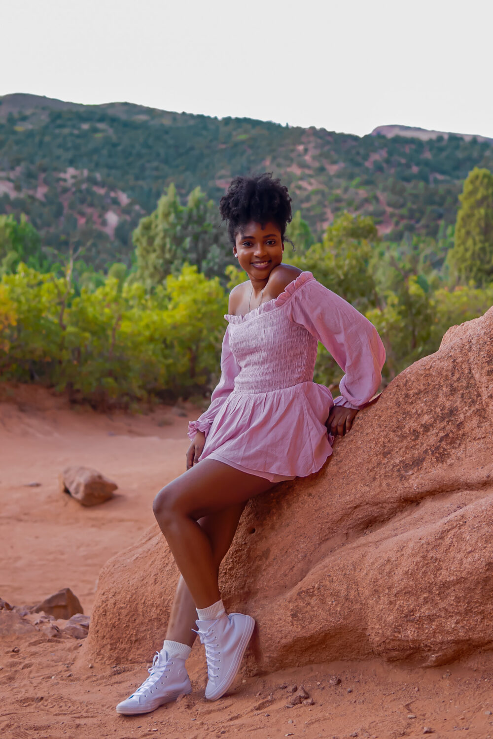 Woman sitting on red rocks outdoors sharing advice on how to overcome a sheltered upbringing and gain independence