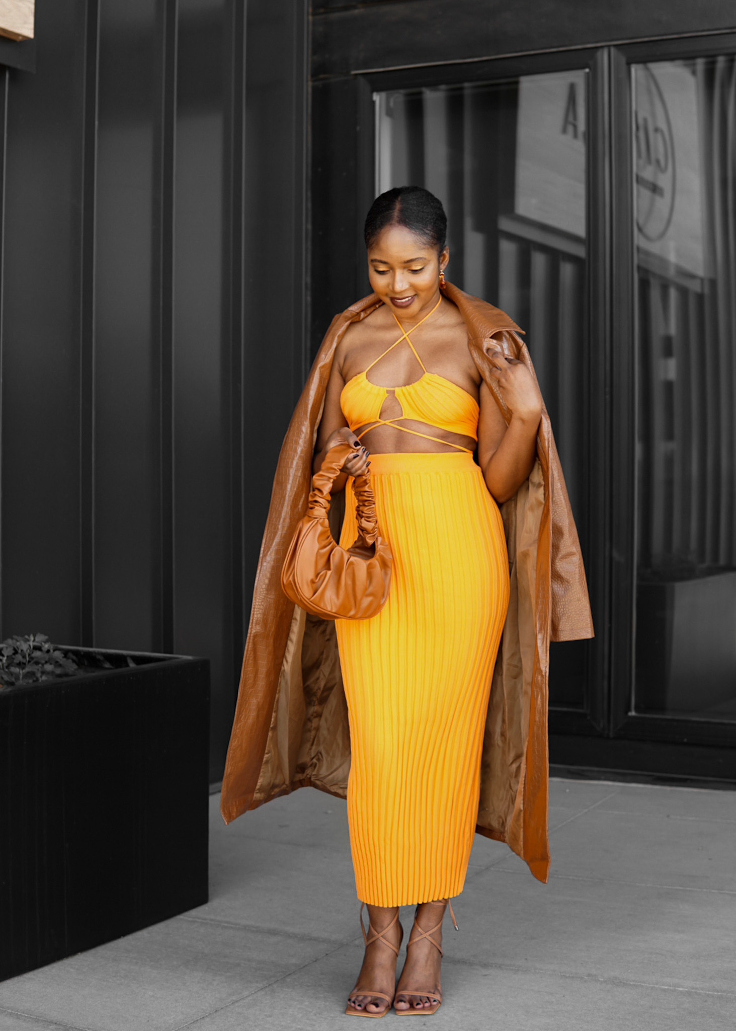 woman poses orange two piece spring summer look brown dumpling bag nude shoes tan trench coat